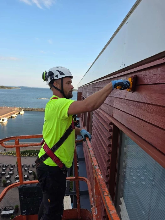 Korkean kerrostalon seinän maalaus henkilönostimella